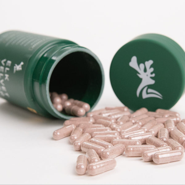 Green pill bottle with pills spilling out on a white background