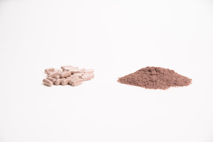 Stack of brown capsules and a pile of brown supplement powder on a white background