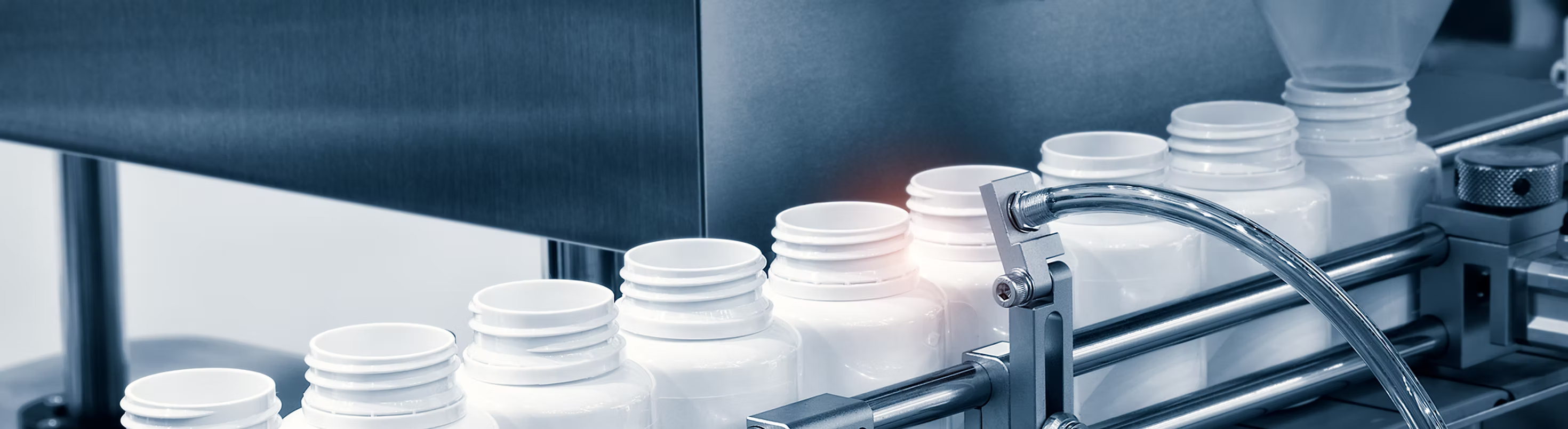 White bottles on a production line with a focus on the bottles and machinery.