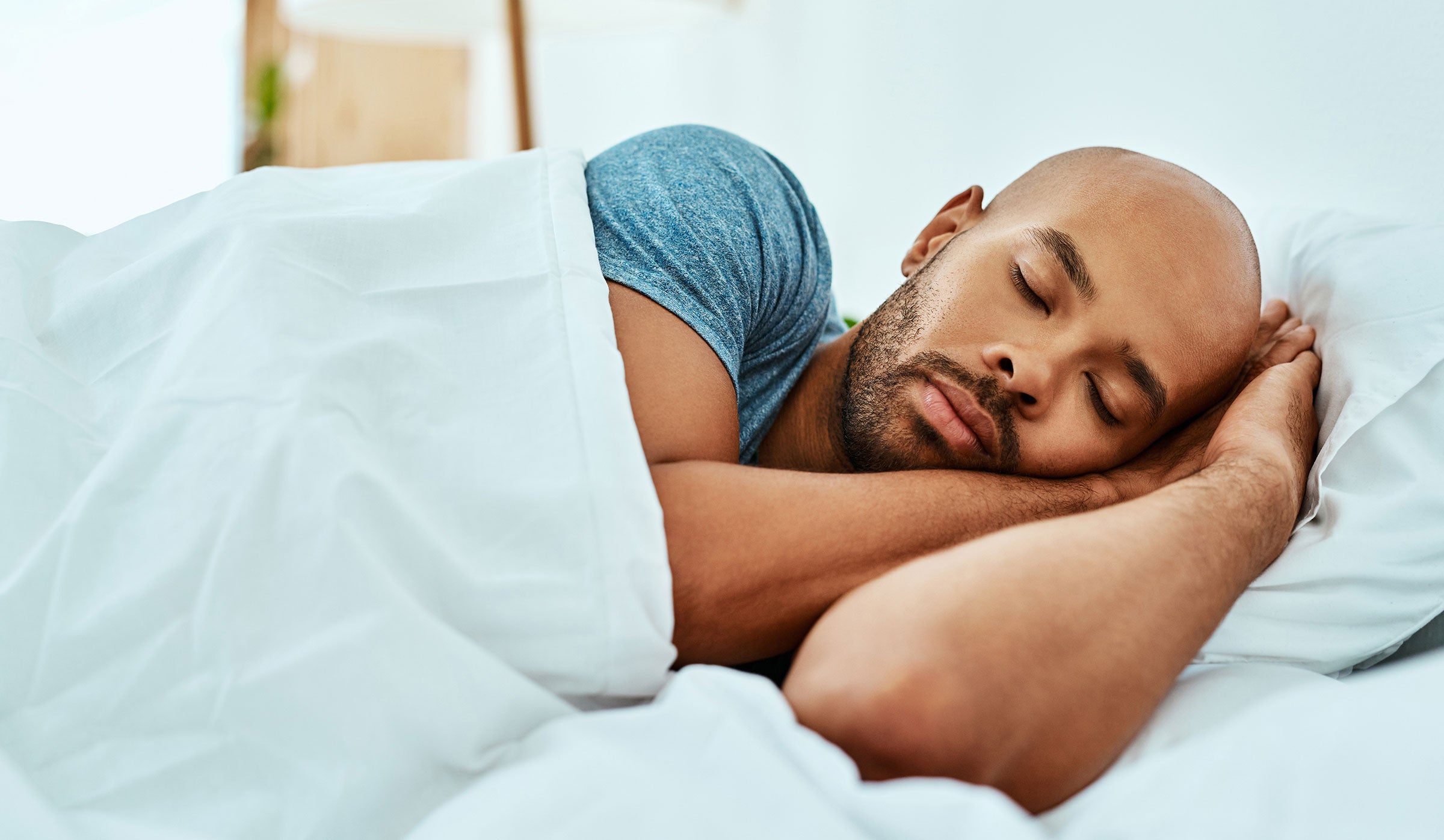 Man sleeping peacefully in bed with white bedding
